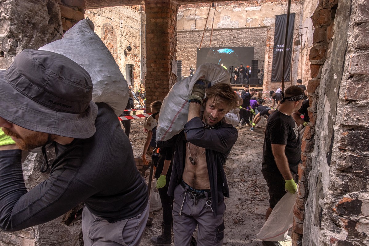 epa10157248 Volunteers from the 'Repair Together' group attending the rave event carry bags with debris as they clean up the local House of Culture that was destroyed during the Russian inva ...