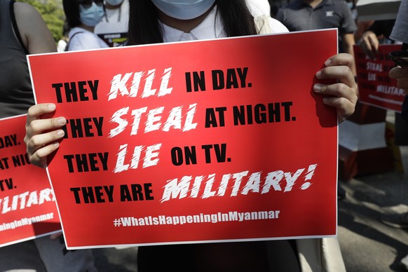 epa09012324 A protestor holds a placard during a protest against the military coup outside the Russian Embassy in Yangon, Myanmar, 14 February 2021. Protests against the military coup continued across ...