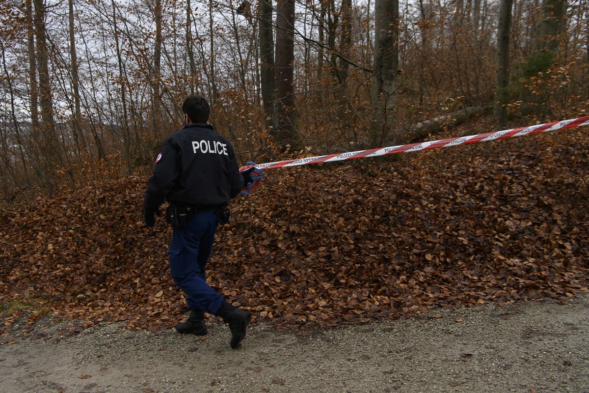 Ein Polizist bringt ein Absperrband am Rande des Koenizbergwaldes an, am Mittwoch, 2. Februar 2022, in Niederwangen. Der leblose Koerper eines achtjaehrigen Maedchens ist am Dienstagabend im Koenizber ...