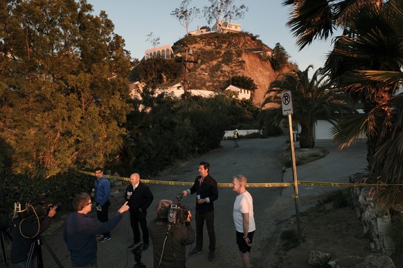 Local news crews report along a closed street at the bottom of hill where a landslide occurred in the Hollywood Hills area of Los Angeles, on Tuesday, Jan. 31, 2017. City inspectors are at a Hollywood ...