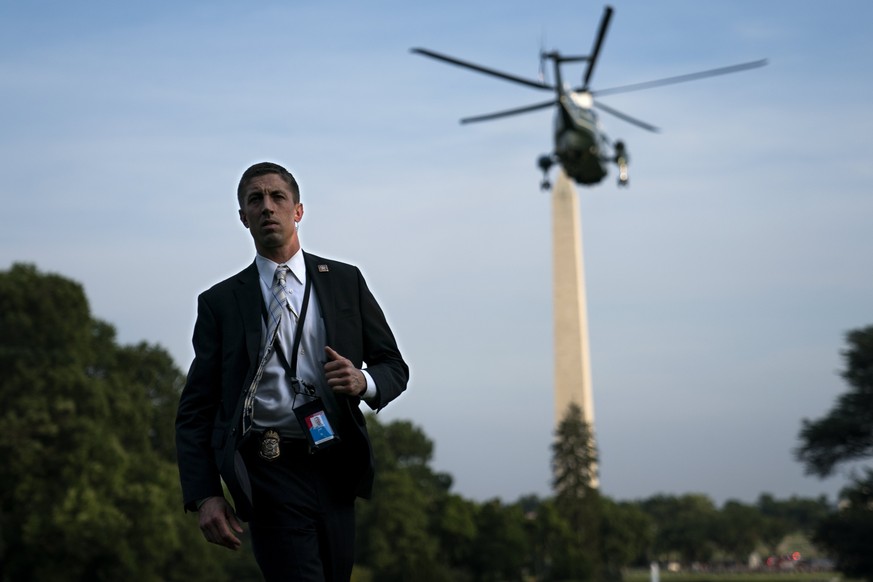 epa06084001 A Secret Service agent looks on as Marine One, with US President Donald J. Trump and First Lady Melania Trump aboard, lifts off the South Lawn of the White House in Washington, DC, USA, 12 ...