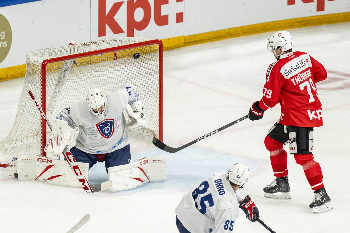 Switzerland's Tyler Moy, not pictured, scores to 2-2 against France's goalkeeper Sebastian Yloenen, left, next to Switzerland's Calvin Thuerkauf during an ice hockey World Cup preparati ...
