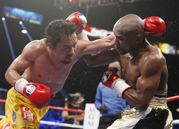 Manny Pacquiao, from the Philippines, left, trades blows with Floyd Mayweather Jr., during their welterweight title fight on Saturday, May 2, 2015 in Las Vegas. (AP Photo/John Locher)