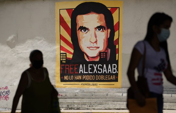 FILE - In this Sept 9, 2021 file photo, pedestrians walk near a poster asking for the freedom of Colombian businessman and Venezuelan special envoy Alex Saab, in Caracas, Venezuela. The Venezuelan gov ...