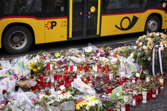 KEYPIX - Ein Postauto faehrt an Blumen und Kerzen vorbei, an der Stelle, an der ein Postauto in Brand geriet, am Sonntag, 15. Maerz 2026, im Zentrum von Kerzers im Kanton Freiburg. Laut der Freiburger ...