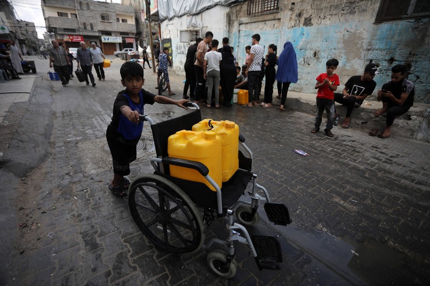 Palestinians queue to refill on water in Rafah refugee camp in the southern of Gaza Strip, Saturday October 14, 2023.. International aid groups and major powers have pleaded with Israel to set up safe ...
