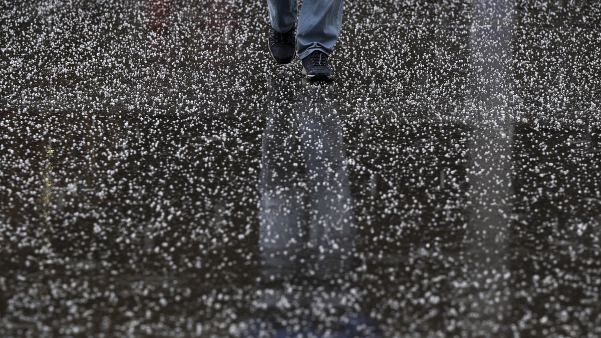 Eine Person laeuft durch einen Hagelschauer, am Donnerstag, 13. April 2023 in Bern. (KEYSTONE/Anthony Anex)