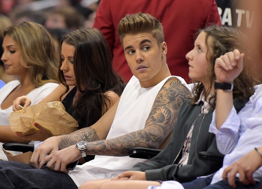 FILE - This May 11, 2014 file photo shows singer Justin Bieber, center, watching the Los Angeles Clippers play the Oklahoma City Thunder with his mother Pattie Mallette, second from left, in the first ...
