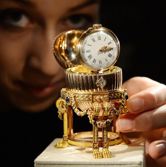 epa04157846 A Wartski Jewellers staff poses with one of the missing Imperial Faberge Eggs in London, Britain, 07 April 2014. One of the missing Imperial Faberge Eggs made for the Russian Royal family  ...