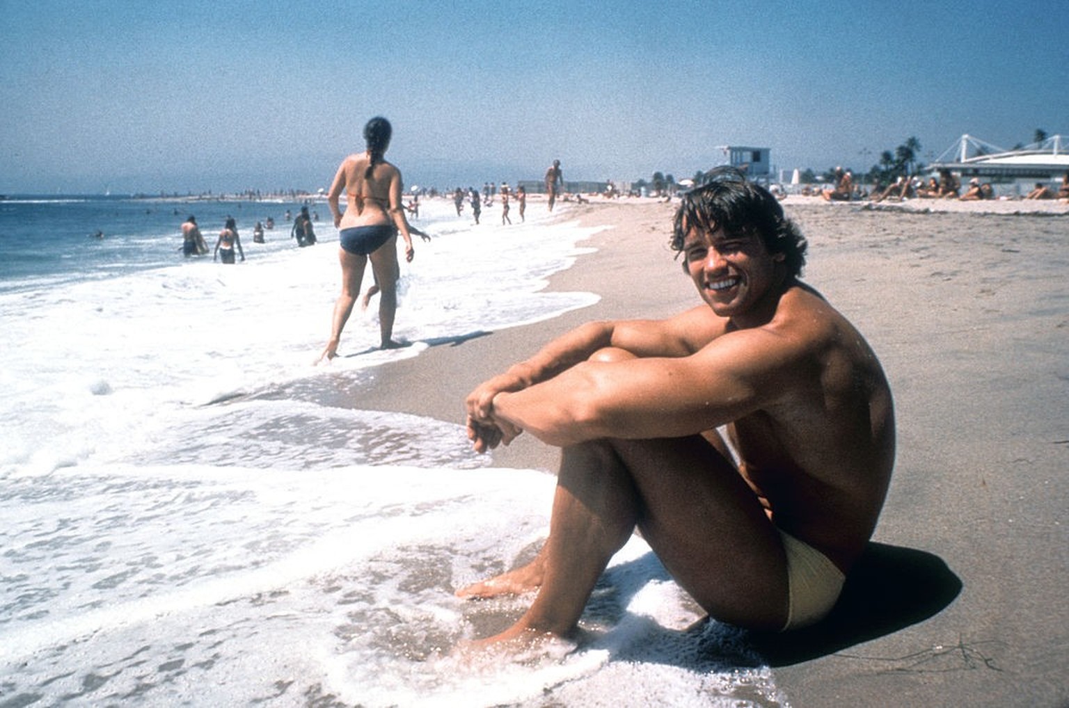 LOS ANGELES - AUGUST 1977: Austrian Bodybuilder Arnold Schwarzenegger sits in the surf on Venice Beach in August 1977 in Los Angeles, California. (Photo by Michael Ochs Archives/Getty Images)