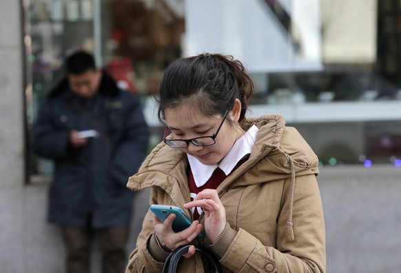 Chinese people check on their smartphones on a street in Beijing Monday, Feb. 16, 2015. On the Internet, in college classrooms and in corporate offices, the Chinese Communist Party has raised the virt ...