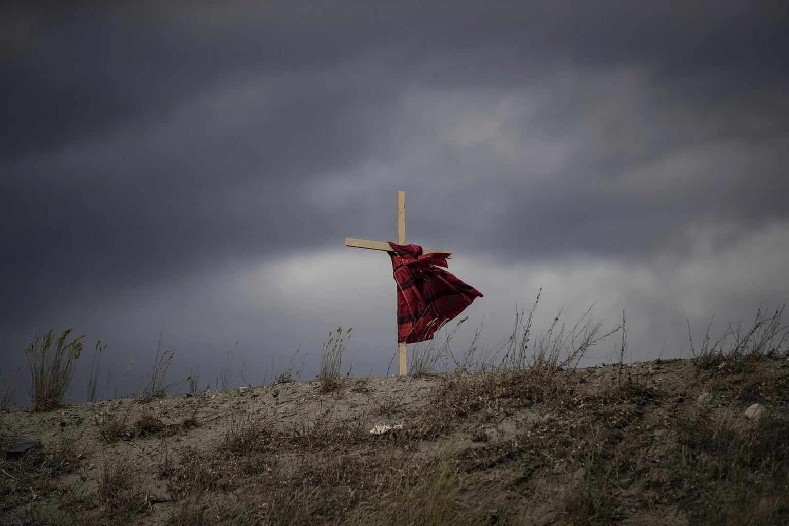 A child's dress hangs on a cross as it blows in the wind near the former Kamloops Indian Residential School, to honor the 215 children whose remains have been discovered buried near the facility Frida ...