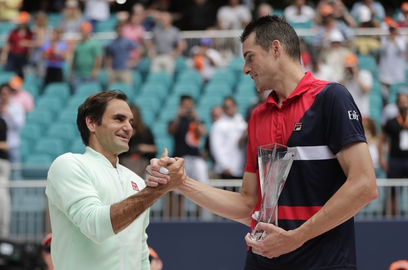 Roger Federer, of Switzerland, left, shakes hands with John Isner, right, after winning the singles final of the Miami Open tennis tournament, Sunday, March 31, 2019, in Miami Gardens, Fla. (AP Photo/ ...