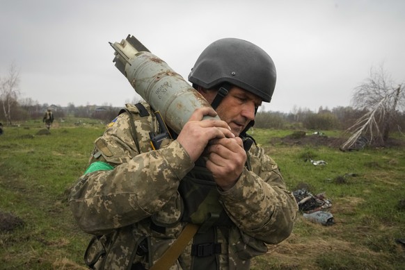 A Ukrainian soldier carries an unexploded Russian air bomb in the village of Kolonshchyna, Ukraine, Thursday, April 21, 2022. (AP Photo/Efrem Lukatsky)