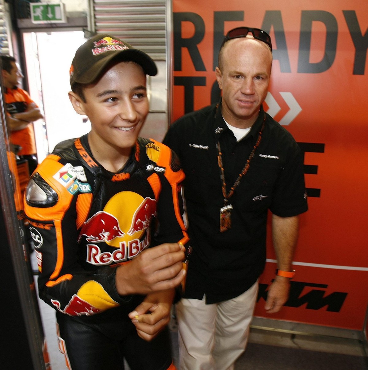 Swiss rookie 125cc motorcycle pilot Randy Krummenacher, left, enters the KTM team box with former motorcycle racer and 13 times Grand Prix winner Randy Mamola from USA prior to the first free practice ...