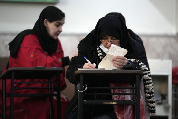 Voters fill out their ballots during the parliamentary and Assembly of Experts elections at a polling station in Tehran, Iran, Friday, March 1, 2024. Iran held the country&#039;s first election since  ...