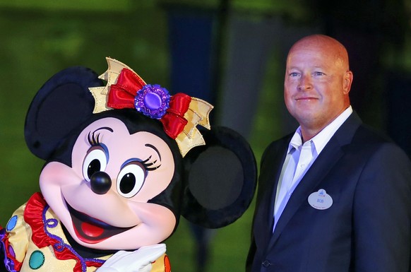 FILE - Chairman of Walt Disney Parks and Resorts Bob Chapek poses with Minnie Mouse during a ceremony at the Hong Kong Disneyland, as they celebrate the Hong Kong Disneyland&#039;s 10th anniversary on ...