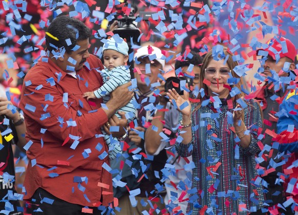 FILE - In this May 4, 2018 file photo, Venezuela&#039;s President Nicolas Maduro holds a baby as first lady Cilia Flores applauds during a campaign rally, in Caracas, Venezuela. Maduro, who presents h ...