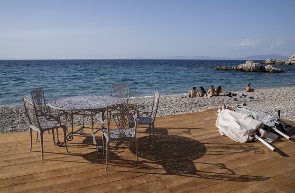 People sit on at a beach in Kokkari , in front of a tavern on the eastern Aegean island of Samos, Greece, Tuesday, June 8, 2021. About a month after Greece officially opened to international visitors, ...