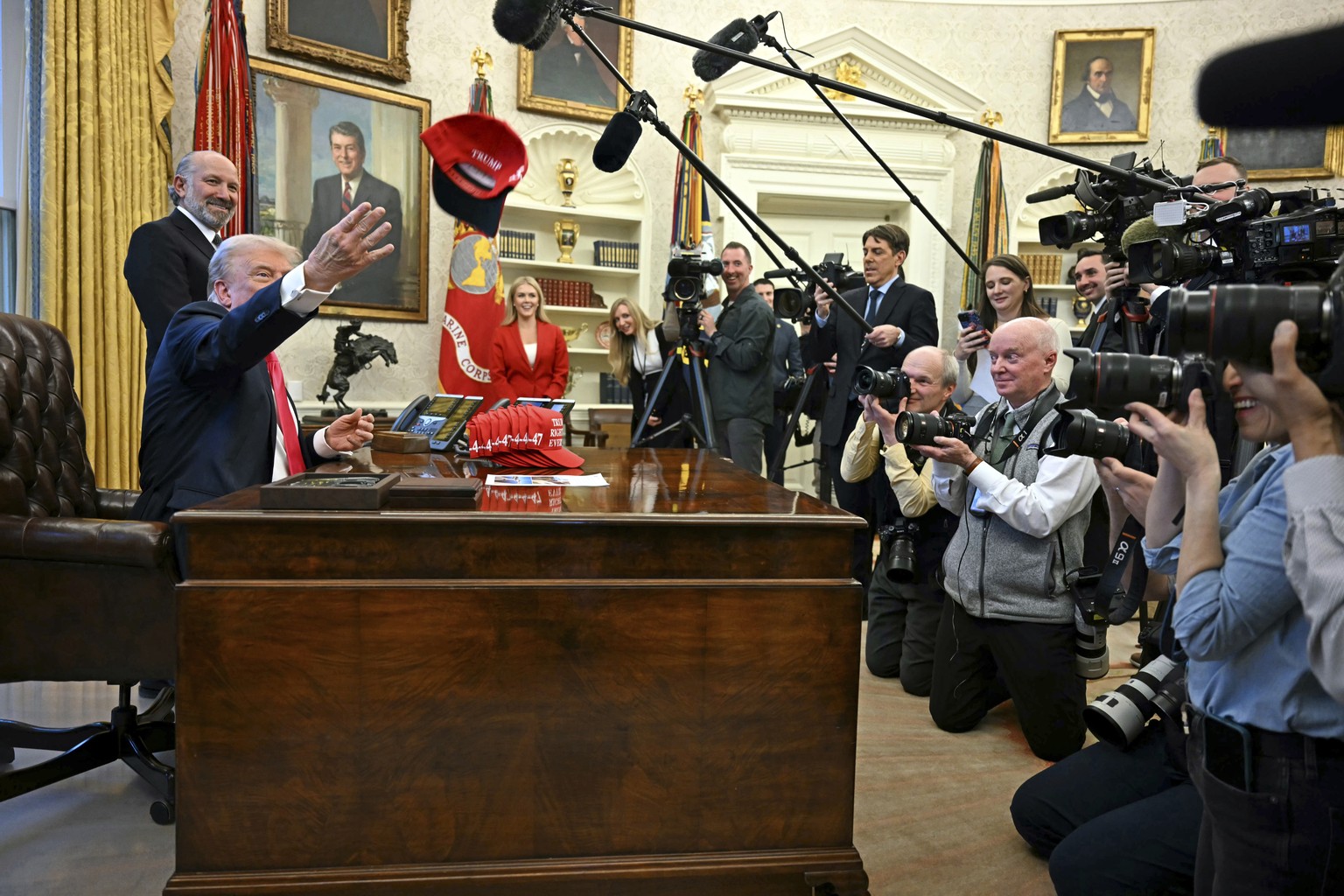President Donald Trump throws a hat that reads &quot;Trump Was Right About Everything&quot; as he talks to reporters while Commerce Secretary Howard Lutnick, and White House press secretary Karoline L ...