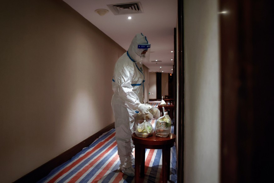 epa10376184 A hotel employee in protective suit delivers food at a quarantine hotel for passengers in Xiamen, Fujian province, China, 22 December 2022. The World Health Organization (WHO) is concerned ...