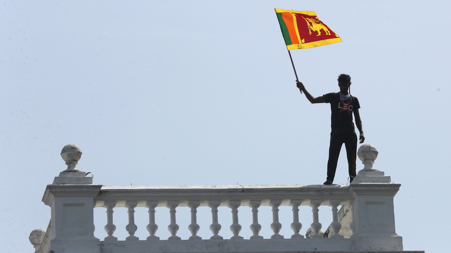 epa10068252 A protester waves the national flag as protesters storm the Prime Minister&#039;s office in Colombo, Sri Lanka, 13 July 2022. Thousands of protesters broke through police barricades and st ...