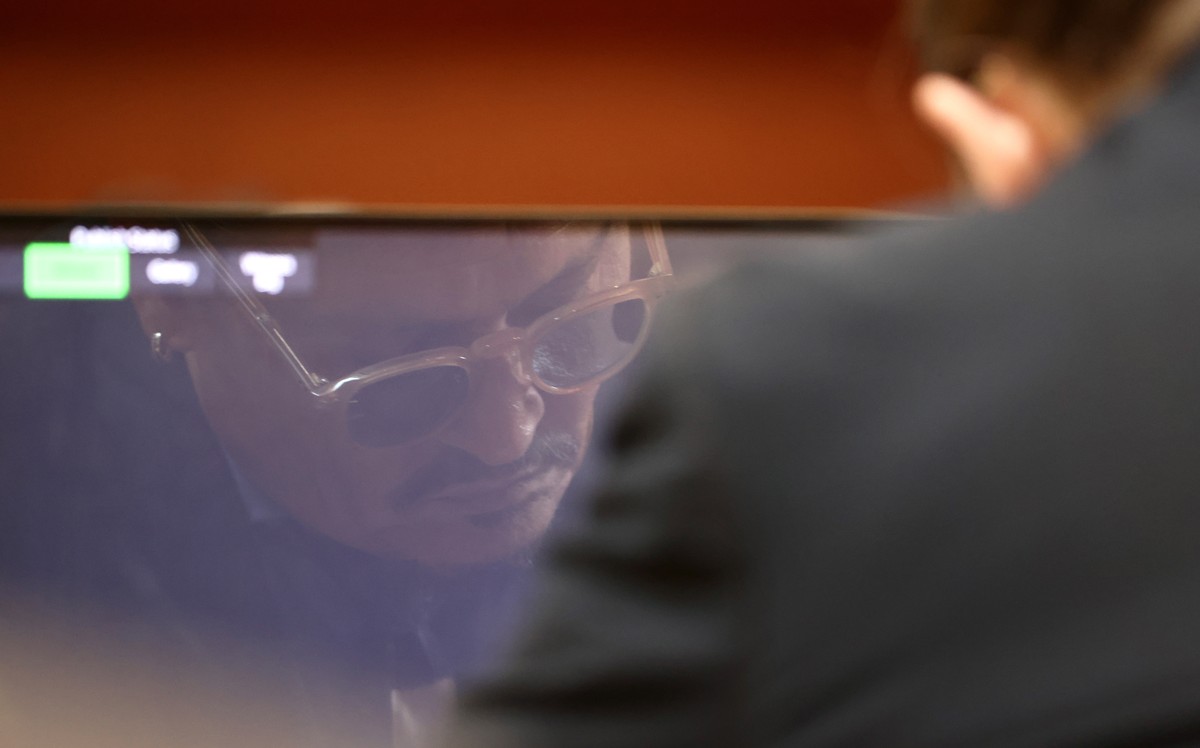 epa09929093 US actor Johnny Depp is reflected in a computer screen as Amber Heard testifies on the stand during the 50 million US dollar Depp vs Heard defamation trial at the Fairfax County Circuit Co ...