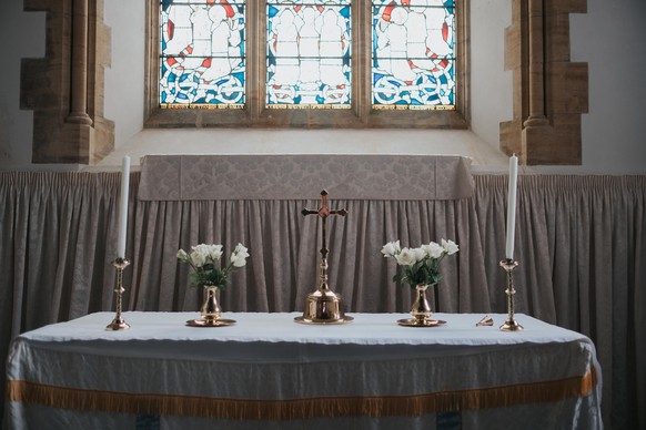 Photograph of a Church of England Altar with a Christian Cross, flowers and candles