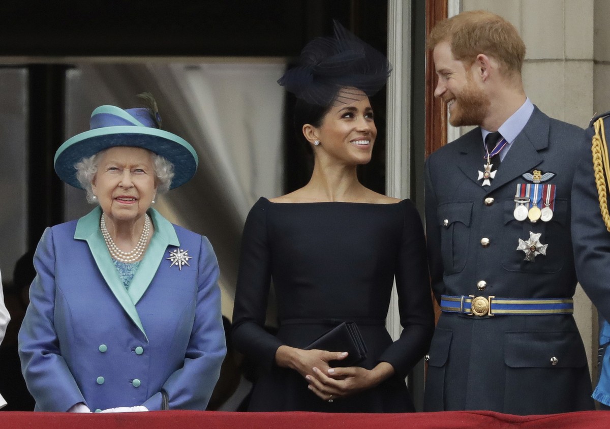 FILE - In this Tuesday, July 10, 2018 file photo Britain's Queen Elizabeth II, and Meghan the Duchess of Sussex and Prince Harry watch a flypast of Royal Air Force aircraft pass over Buckingham P ...