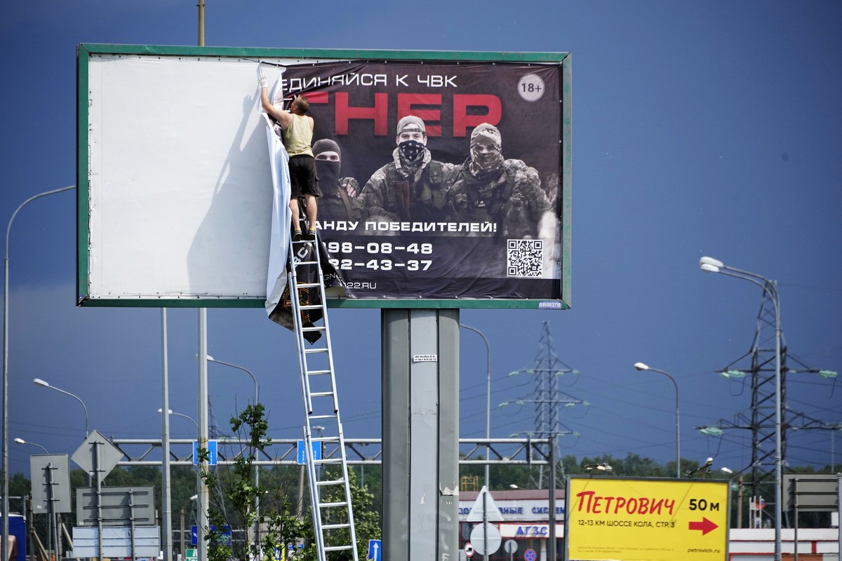 FILE - A man takes down the poster with writing reading "Join us at Wagner", which is associated with the owner of the Wagner private military contractor, Yevgeny Prigozhin, is seen above a  ...