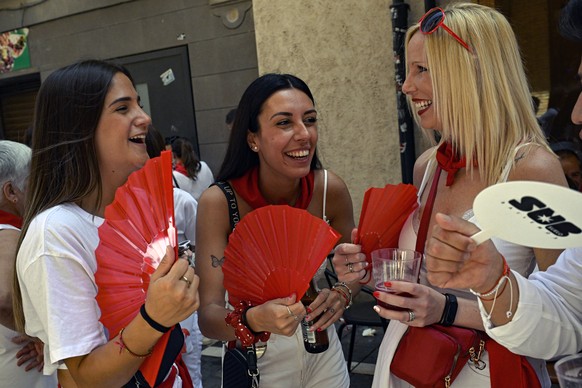 Revellers dressed in white and red, the San Fermin&#039;s colours, cool off from the heat with fans during the San Fermin fiestas in Pamplona, northern Spain, Monday, July 10, 2023. (AP Photo/Alvaro B ...