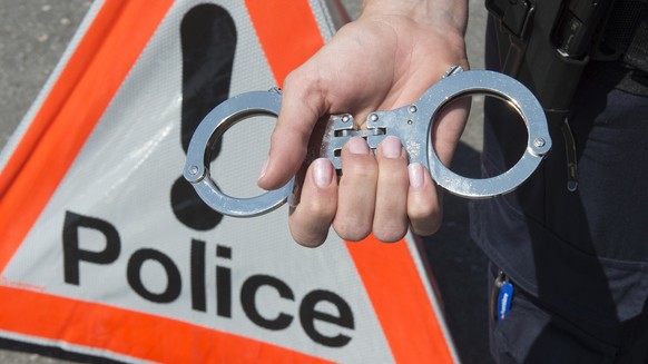 Un policier de la Police cantonale neuchateloise tient des menottes devant un signe police, le 5 juin 2015, a Neuchatel. (KEYSTONE/Sandro Campardo) 

Ein Polizist der Kantonspolizei Neuenburg mit eine ...