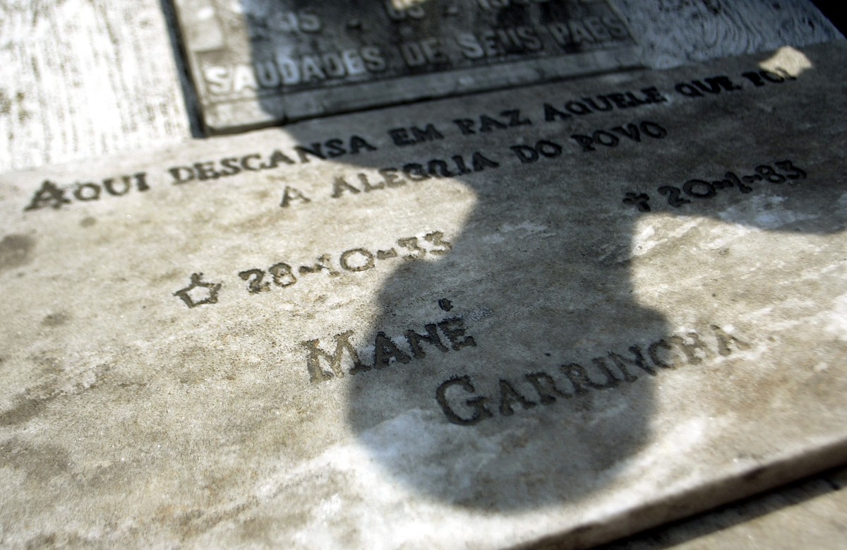 A man casts his shadow over the grave of former Brazilian soccer player Mane Garrincha, with an inscription that's read: "Here rests in peace the one who was the Joy of the People - Mane Gar ...