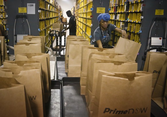Miracle Stewart, right, an employee of Amazon PrimeNow, prepares bags to fill with orders from customers making last minute holiday purchases, Wednesday Dec. 21, 2016, at a distribution hub in New Yor ...