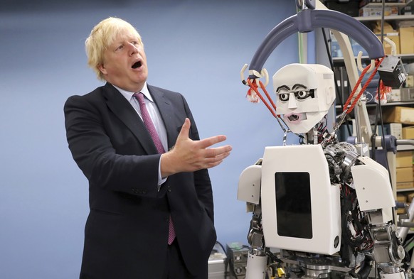 FILE - In this Thursday, July 20, 2017 file photo Britain's Foreign Secretary Boris Johnson gestures as he looks at a humanoid robot at Research Institute for Science and Engineering at Waseda Un ...