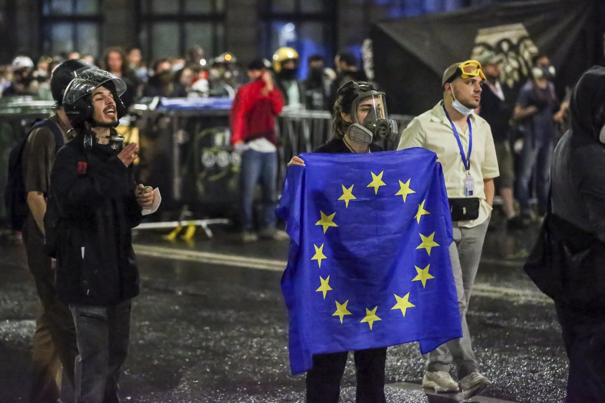 A demonstrator stands with a EU flag in front of police block during an opposition protest against "the Russian law" near the Parliament building in Tbilisi, Georgia, on Wednesday, May 1, 20 ...