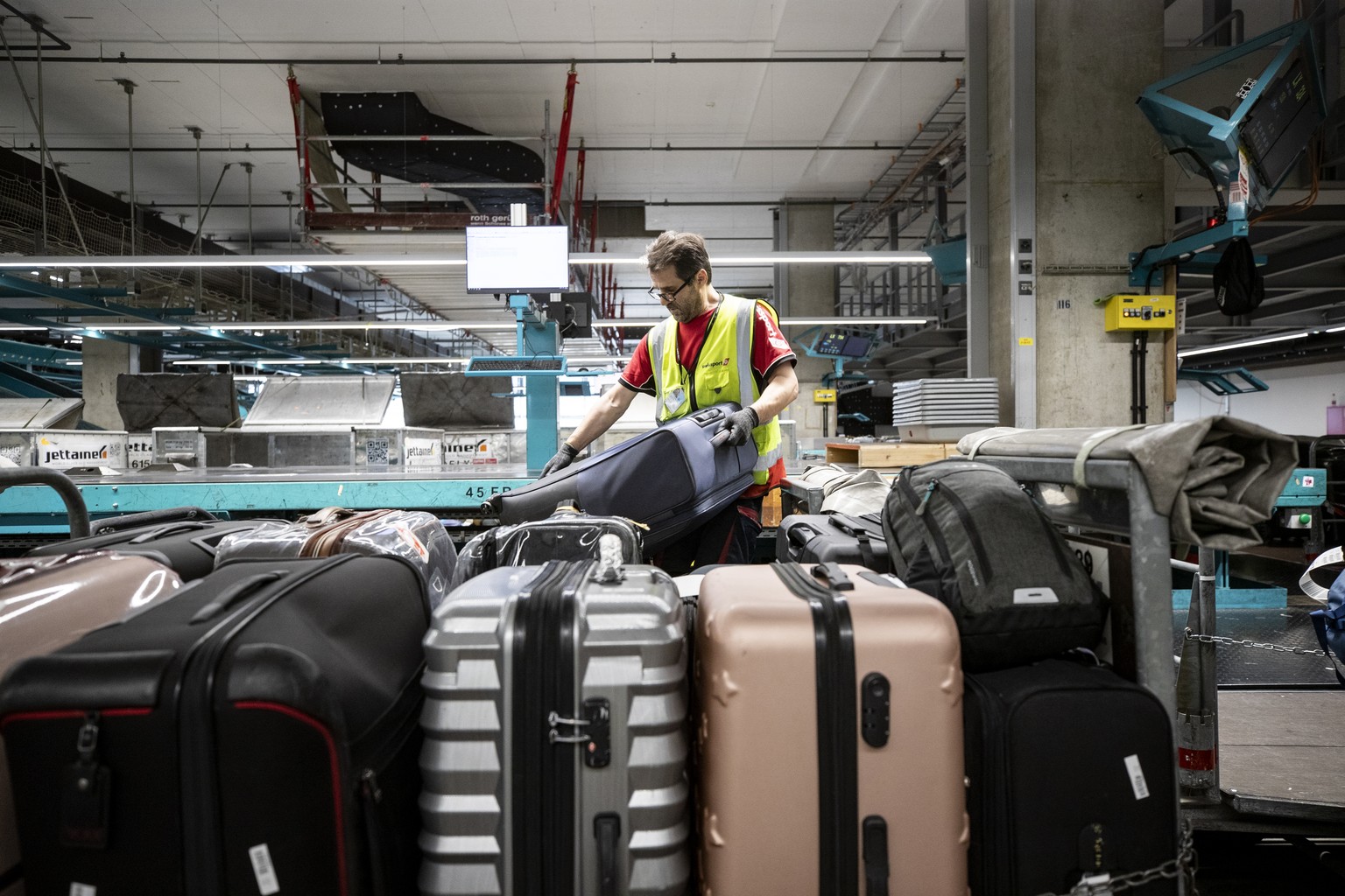 Ein Gepaecksortierer von Swissport arbeitet in der Gepaecksortierung am Flughafen Zuerich am Dienstag, 12. Juli 2022. (KEYSTONE/Alexandra Wey)
