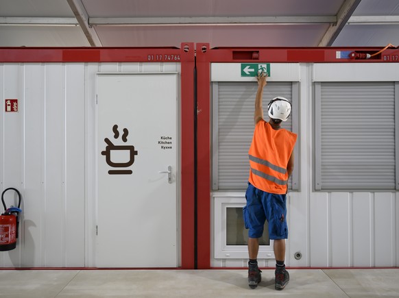 Ein Bauarbeiter bringt ein Notausgangsschild an einem Wohncontainer an, waehrend einem Point de Presse der Stadt Bern zur Eroeffnung des Containerdorf fuer Ukraine-Fluechtlinge, am Mittwoch, 6. Juli 2 ...