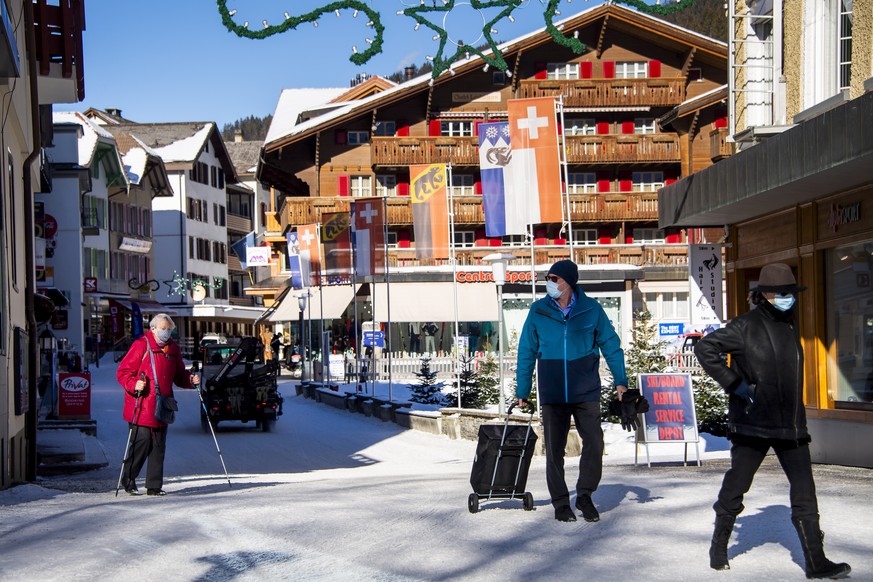 epa08931286 People wearing protective masks are walking down the street of the mountain village while preperations for the FIS Alpine Skiing World Cup in Wengen make progress amid the Coronavirus dise ...