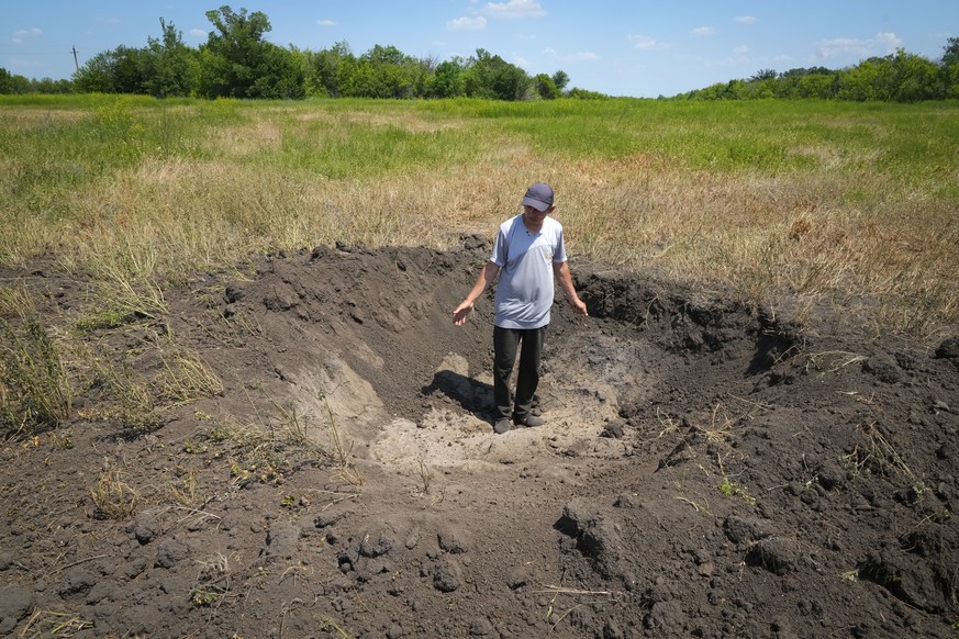 Farmer Serhiy, a local grain producer, shows a crater left by a Russian shell on his field in the village of Ptyche in eastern Donetsk region, Ukraine, Sunday, June 12, 2022. Serhiy claims he cannot s ...