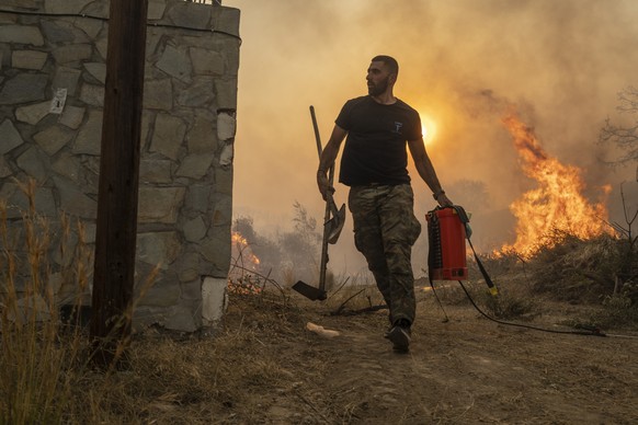 Ilias Kyriakou, 25, runs to extinguish a wildfire burning in Gennadi village, on the Aegean Sea island of Rhodes, southeastern Greece, on Tuesday, July 25, 2023. A firefighting plane has crashed in so ...