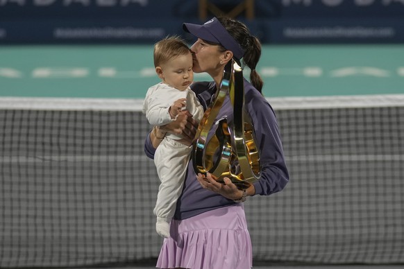 Belinda Bencic of Switzerland kisses her daughter while holding the winning trophy during award ceremony after winning against Ashlyn Krueger of United States in the Women&#039;s single final match of ...