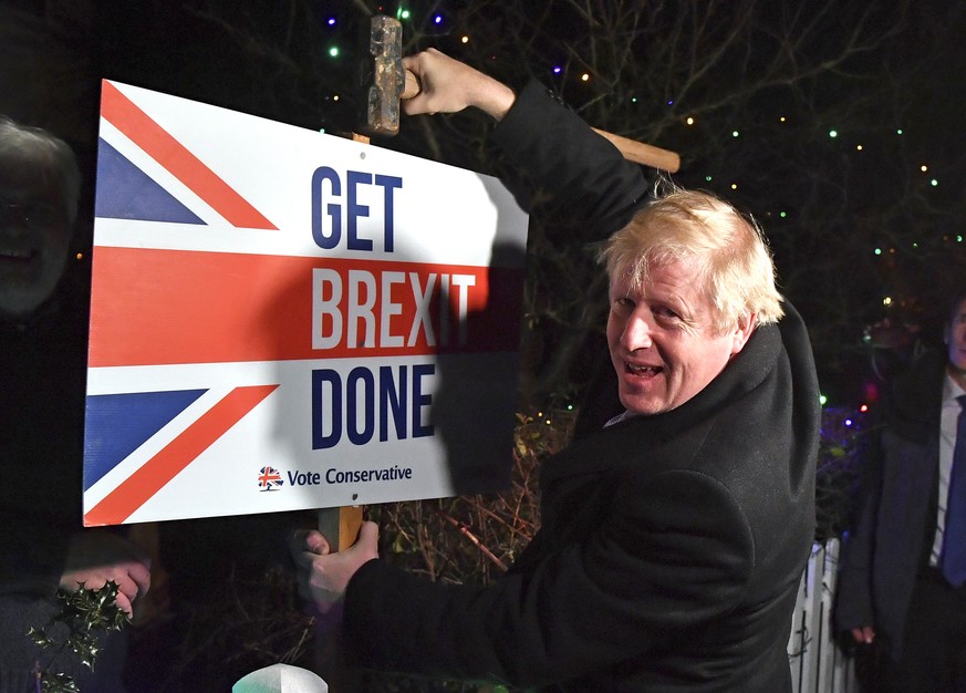 FILE -- In this Wednesday, Dec. 11, 2019 file photo, Britain's Prime Minister and Conservative party leader Boris Johnson poses as he hammers a &quot;Get Brexit Done&quot; sign into the garden of a su ...