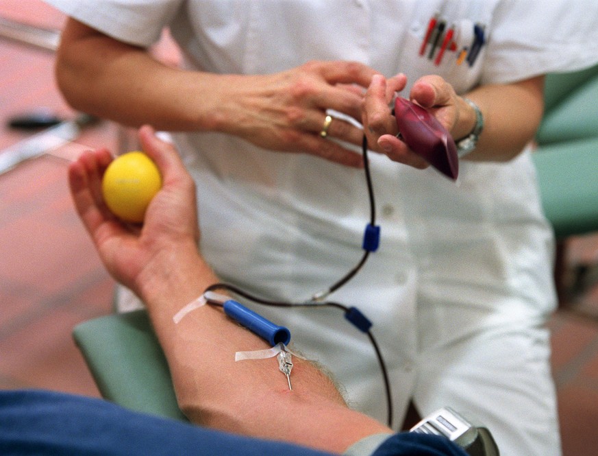 Eine Mitarbeiterin des Blutspendedienstes Zuerich hilft einem freiwilligen Spender beim Blutspenden, aufgenommen am 2. Juli 2003 im Blutspendedienst ZH des Limmattal-Spitales in Schlieren. (KEYSTONE/M ...