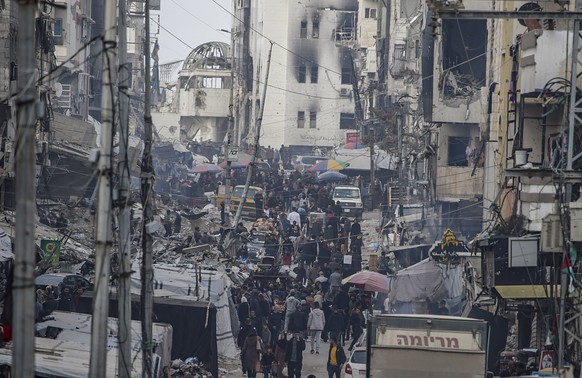 epa11866139 Palestinians walk past damaged buildings in Al Wihda street, Gaza City, 31 January 2025. Israel and Hamas implemented the first phase of a hostage release and ceasefire deal on 19 January  ...