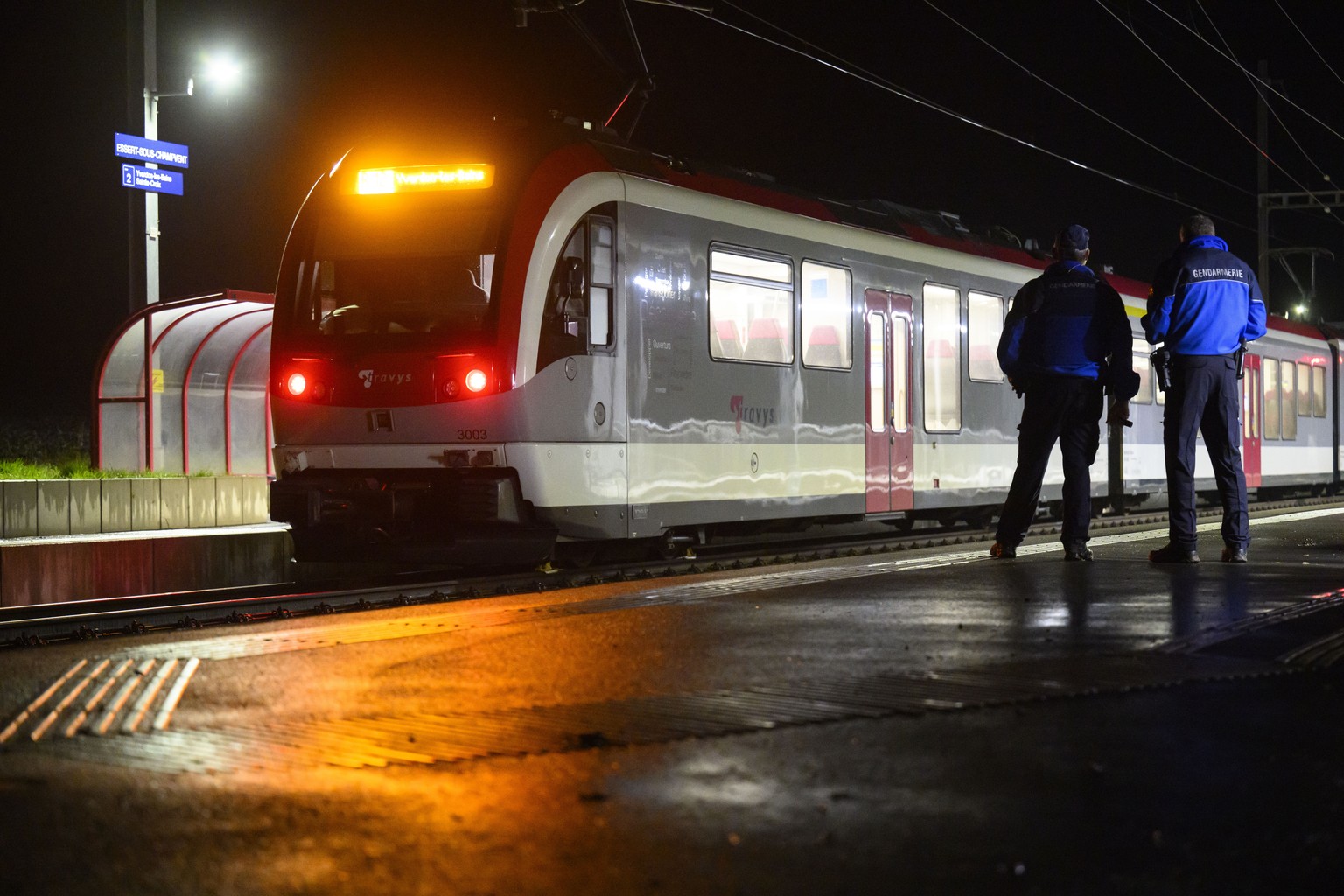 Two Vaud cantonal police officers watch the Travys train where a hostage-taking incident took place at Essert-sous-Champvent station, Switzerland, Thursday, 8, February, 2024. A hostage-taking inciden ...