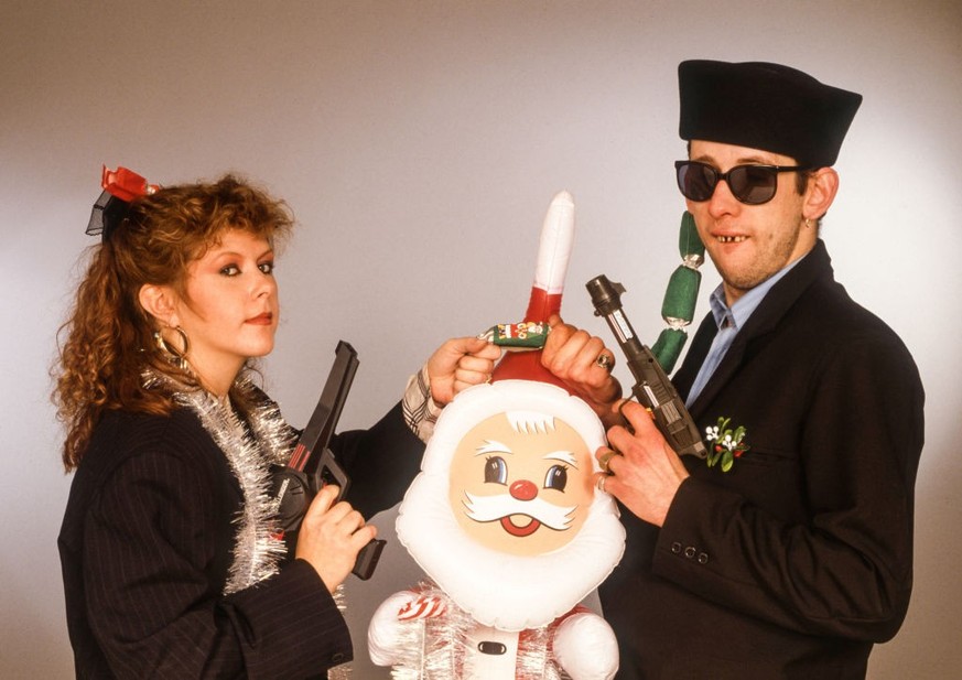 Portrait of British musician Kirsty MacColl (1959 - 2000) and Irish musician Shane MacGowan, the latter of the group the Pogues, as they pose together, each holding a toy gun with one hand and, in the ...