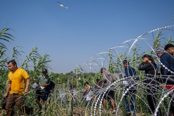 EAGLE PASS, TEXAS - MAY 21: Migrants from El Salvador walk through brush alongside the banks of the Rio Grande after crossing into the U.S. on May 21, 2022 in Eagle Pass, Texas. Title 42, the controve ...