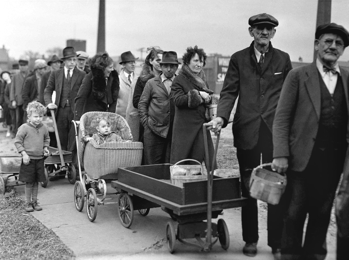 FILE - In this May 9, 1938 file photo, people stand in line for their portions of a federal surplus of potatoes and cabbages in Cleveland. Nearly a century later, the U.S. economy is all but shut down ...