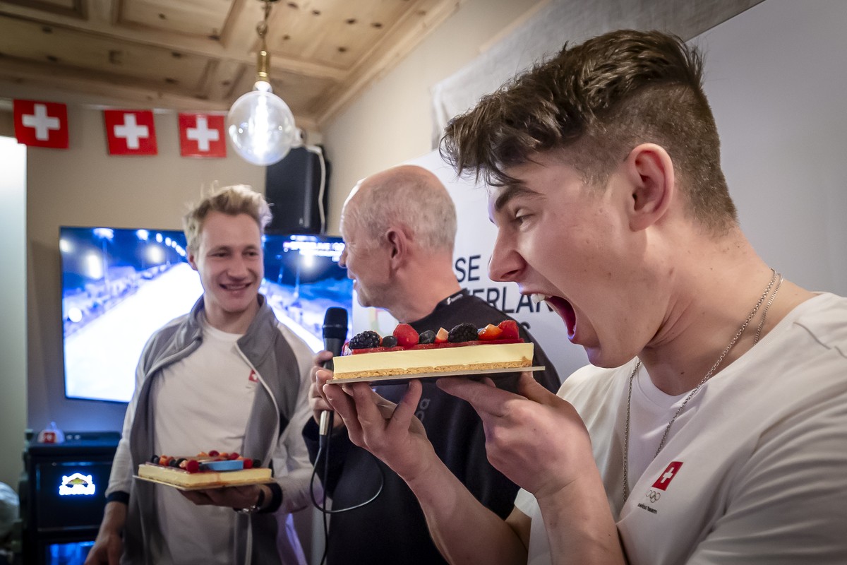 Gold medalist Switzerland's Franjo von Allmen, right, pretends to bite into a cake with a gold medal he received next to bronze medalist Marco Odermatt, left, during a welcome at the House of Swi ...